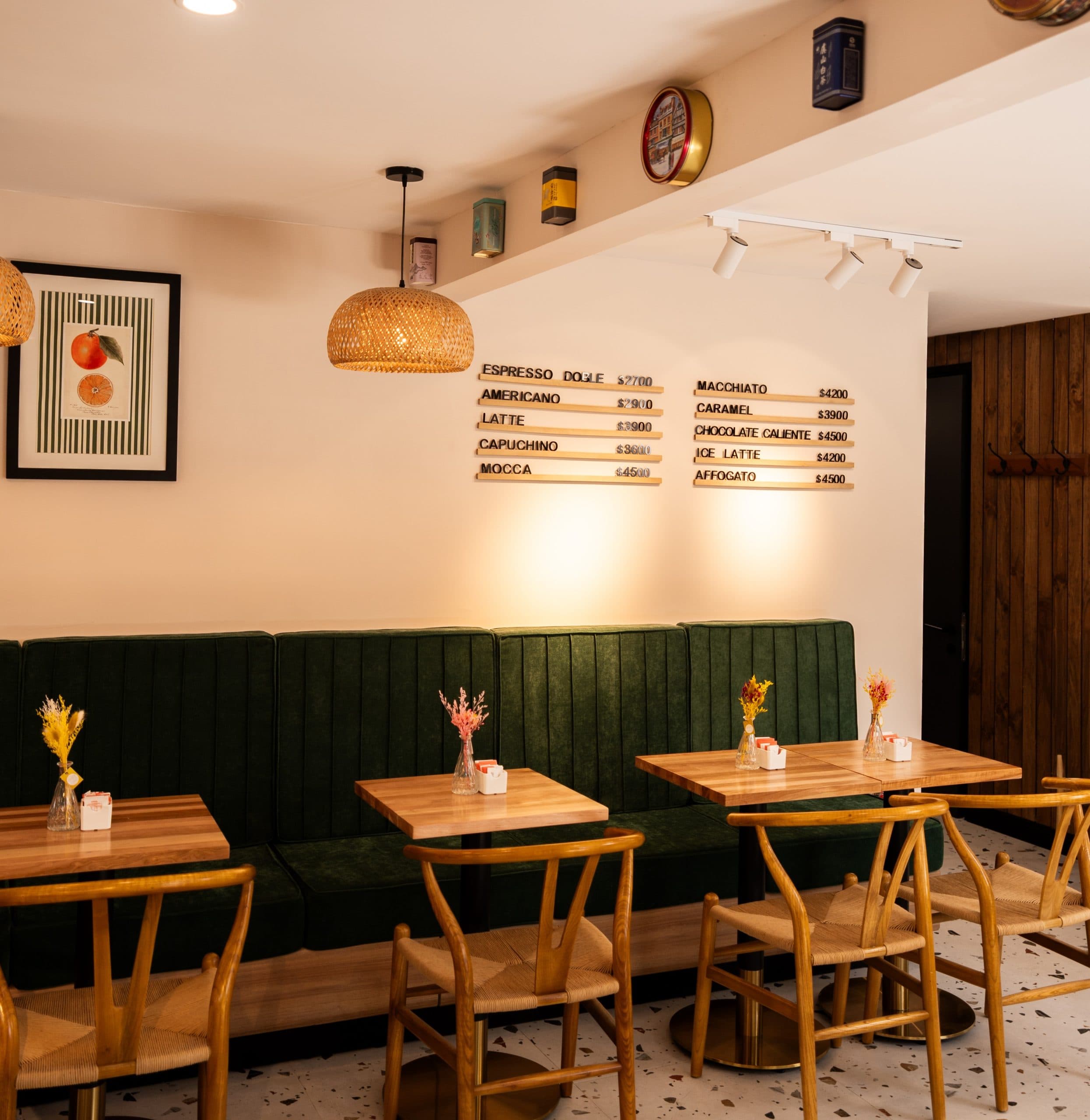 Interior Portokali Café — sofá verde, menú en madera, lámpara rattan